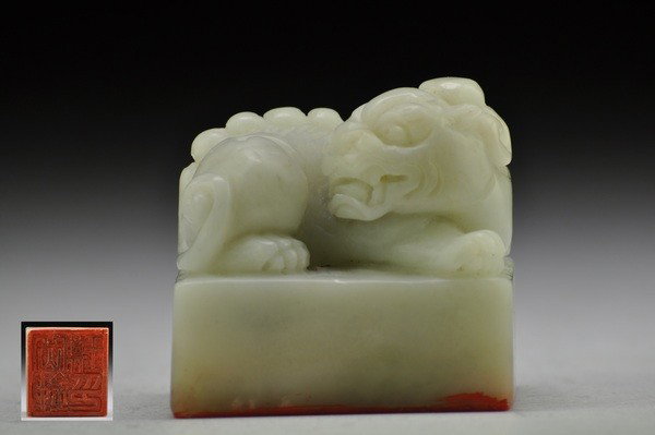 A SOAPSTONE LION SEAL.: Well carved with a recumbent lion resting on one front paw,the other outstretched as it turns its head to the side,the details of the long mane and tail finely incised,the base carved with a inscripti