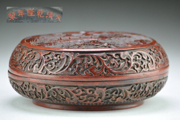 A CHINESE CINNABAR LACQUER CIRCULAR BOX AND COVER,: carved in relief on the cover with a medallion depicting bearded elders and young attendants gathered beneath pine within a keyfret border, the sides with smaller quatrefoil divided by formal peony sc