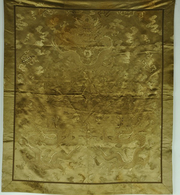 A YELLOW SILK GROUND EMBROIDERED HANGING.(QING DYN: Displaying three dragons worked in couched gilt-wrapped striding amid cloud scroll in brightly colored silk floss.31 1/2''x 27''
