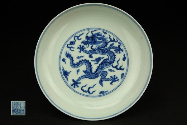 A BLUE AND WHITE DRAGON DISH.(MARK AND PERIOD OF QI: painted with a writhing dragon chasing a flaming pearl amongst flame scrolls six character mark on base. 1 1/8''H 8''Diam
