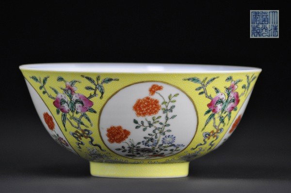 A FAMILLE -ROSE YELLOW-GROUND 'MEDALLION' BOWL .(M: The exterior finely enameled with four roundels enclosing sprays of roses, asters and lingzhi, separated by fruiting and flowering peach branches tied with a wan emblem above froth-caped waves, all re