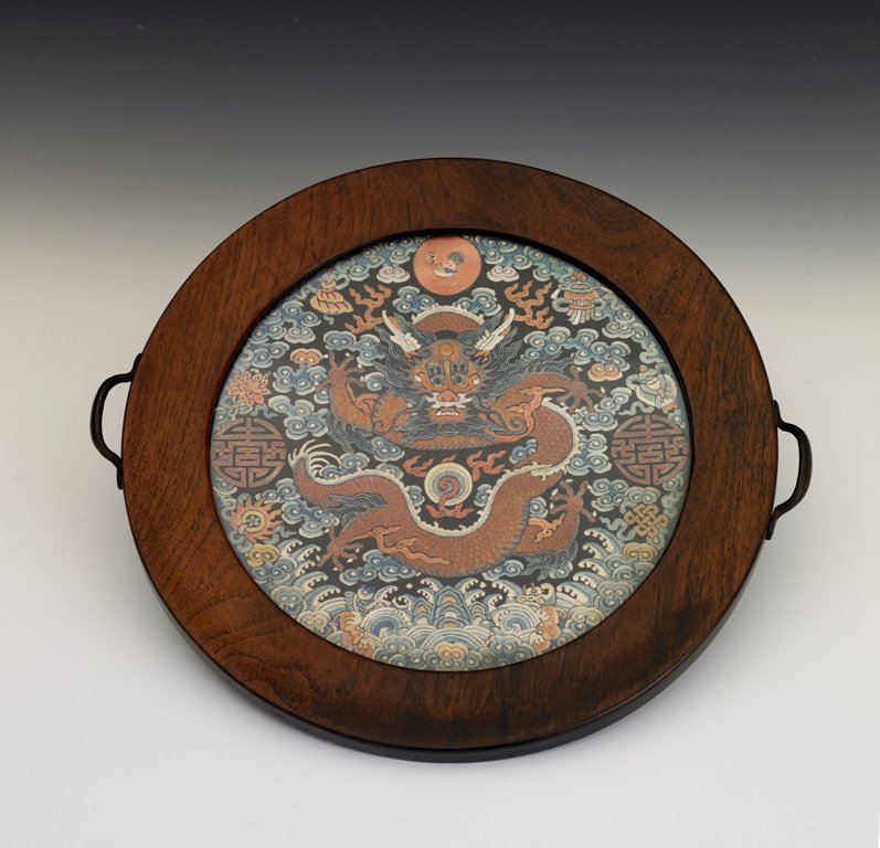 A embroidered dragon roundel, Qing Dynasty: Qing Dynasty Embroidered in satin stitch and fine couched gold thread with a front-facing imperial dragon, the sinuous body couched in fine gold thread against a ground of wispy clouds embroidered in 
