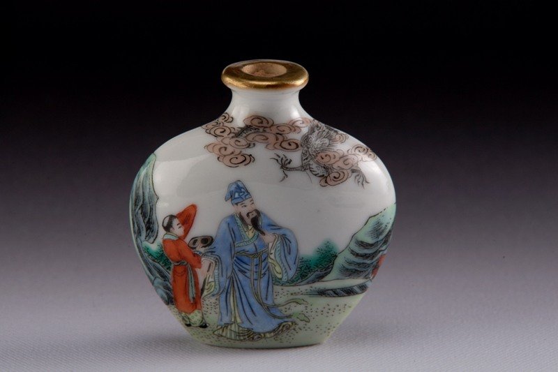 A famille -rose porcelain snuff bottle, MARK OF QIAN: MARK OF QIANLONG Marble white colored with three individuals watching a flaming dragon in the clouds, a rocky landscape. Four Chinese characters on the bottom. 2 1/2 in. tall.