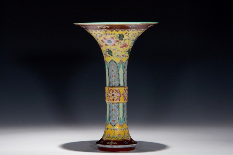 A famille-rose yellow-ground gu-form vase, 18TH CEN: 18TH CENTURY Narrow- shaped vase decorated with mixture of blue, purple and maroon colors. Numerous blossoming flowers on the neck of the vase. Marked Seal. 8 3/8 in. tall.