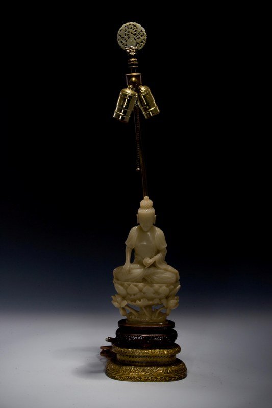 A soapstone carving of Buhhda, 19TH CENTURY: 19TH CENTURY This a lamp stand, the stand is a white- jade tone soapstone of a Buddha in a seated position. Seated on a double golden- yellow lotus base. On the top of the light stand there is another