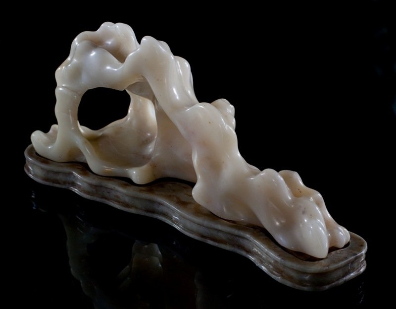 A soapstone boulder and stand,: Irregular shape with a white soapstone even tone. With collisions and inclusions. On a soapstone base . 3 3/4''x 8'' x 2'.