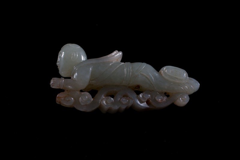 A white jade carving of a boy, 19TH CENTURY: 19TH CENTURY Crystal/ dark jade white tone, carving of a young boy in a plank position on a cloud- form structure. 2 3/4'' tall