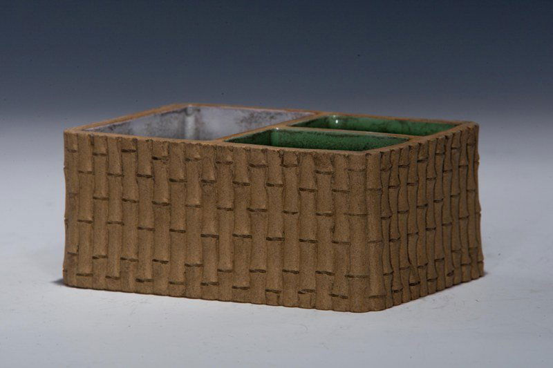 A yixing brush washer, REPUBLIC PERIOD: REPUBLIC PERIOD Mud- brown tone in the exterior of the washer with bamboo- like designs. The interior is seperated into three sections, two of them are spinach- green colour. There is also a sticker i