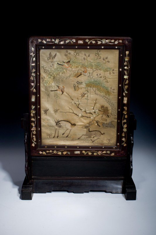 A Chinese silk inlaid wood table screen, 19TH CENT: 19TH CENTURY Antique Chinese hand embroidered silk screen depicting deer, monkey, butterflies, insects, flowers, trees and paradise birds. Mounted in wooden table screen frame with mother of pearl inl