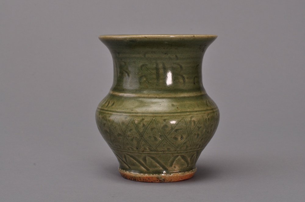 A CELADON LONGQUAN ZHADOU: 元-明 龍泉釉渣斗 YUAN-MING DYNASTY The vase is narrow globular- shaped and light brown color tone overall. 4 7/8 in. (12.3 cm) diameter, 5 7/8 in. (15 cm) tal