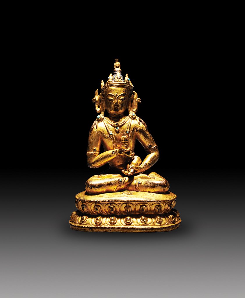 A GILT-BRONZE FIGURE OF VAJRASATTVA: MING DYNASTY Seated in dhyanasana, the hands held before the chest in dharmachakra mudra, dressed in long flowing robes with delicately incised hems, the face with a gentle smile and downcast eyes, al