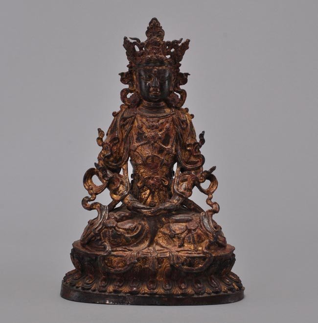 A GILT-LACQUERED BRONZE FIGURE OF BUDDHA: MING DYNASTY Seated in vajrasana on a double-lotus base, his hands in dhyanamudra, wearing flowing robes, curly headdres surmounted by ushnisha, elongated earlobes and meditative expression 16 1/8 in.
