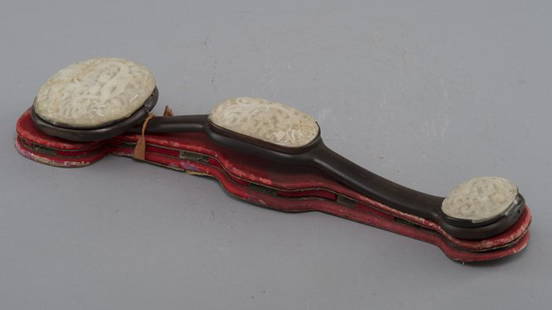 A CARVED WHITE JADE AND ROSE WOOD RUYI SCEPTER: QING DYNASTY The dark hardwood scepter is inset with three shaped jade plaques,finely carved with dragons. 17 7/16 in. (44.3 cm) long.