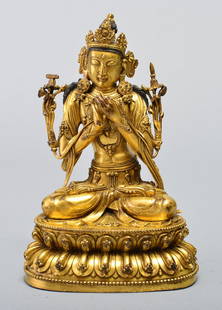 A GILT-BRONZE FIGURE OF MANJUSRI BODHISATTVA: MING DYNASTY Seated in vajrasana on a separate cast lotus base, both hands crossed in front of the breast and holding vajra and ghanta, wearing pleated dhoti, scarf. 9 1/16 in. (23 cm) tall.