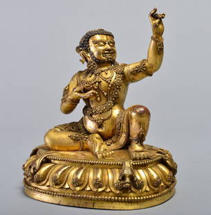 A GILT-BRONZE FIGURE OF MAHASIDDHA: MING DYNASTY Seated upon a flayed antelope draped over a lotus pedestal, with his right leg bent at the knee and resting on the ground with the sole of his foot turned upward, his left knee raised wit