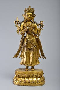 A GILT-BRONZE FIGURE OF AVALOKITESVARA: MING DYNASTY the figure standing on a lotus base with hands in dharmacakra mudra, each holding the stem of a lotus that rises to the shoulder. The face of the figure shows a benevolent expression with