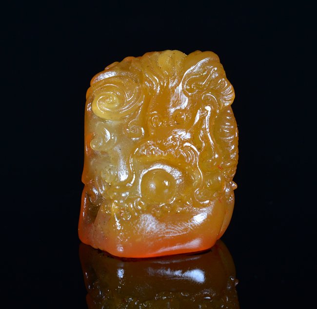 A CARVED TIAN HUANG STONE SEAL: the soapstone is of rectangular-shaped and the exterior is decorate with a dragon chasing a flaming pearl. The base of the stone has a marked seal. 19.9g 1 5/16 in. (3.3 cm) tall.