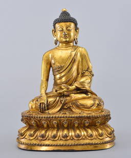 A GILT-BRONZE FIGURE OF SAKYAMUNI BUDDHA: Ming Dynasty Seated in dhyanasana on a double-lotus base with the hands in bhumisparsamudra, clad in a diaphanous sanghati with beaded hems, the face with serene expression centered by a raised urna a