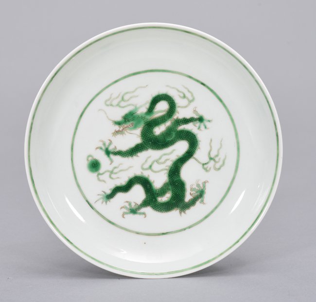 A GREEN-GLAZED DRAGON DISH: Mark And Period Of QianLong The dish is of concave-shaped, the interior center is decorated with a green dragon chasing a flaming pearls and surrounded by ruyi clouds. The exterior is decorated with p