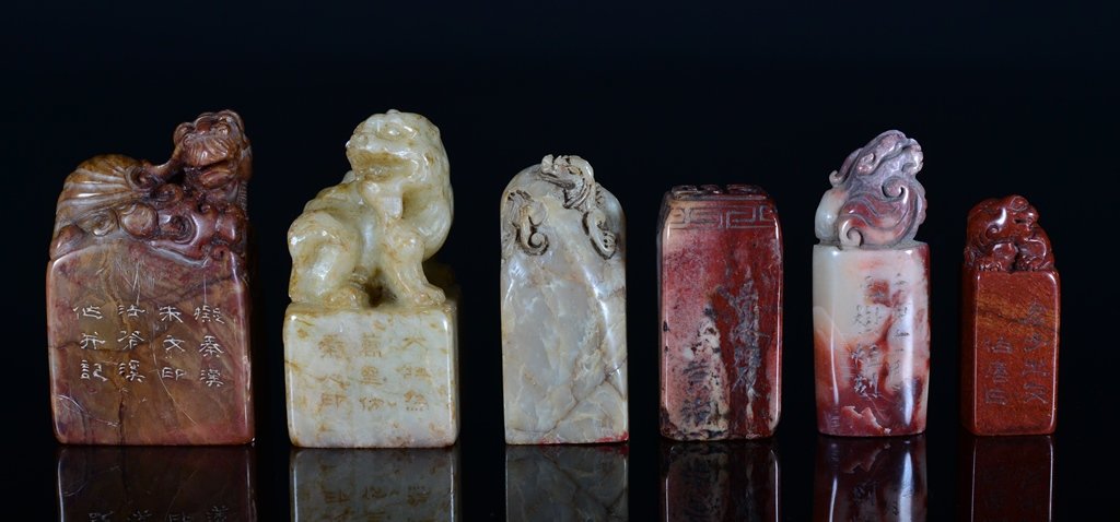A SET OF SIX SOAPSTONE SEALS: The six soapstone seals are rectangular or square-shaped. Four of the six seals is decorated with a seated lion on the top of the seal. Five of the six seals is decorated with Chinese writings. 2 9/16