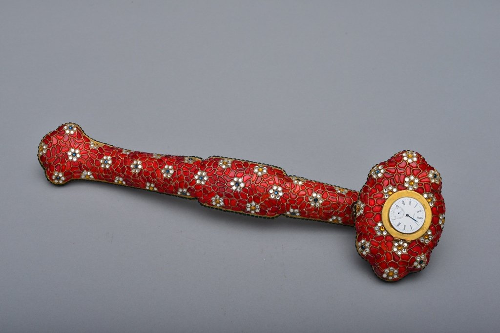 A CLASS INSET GILT-BRONZE RUYI SCEPTRE: Mark of QianLong The scepter is overall a red color tone. The head of the scepter is decorated with a clock. The handle of the scepter is decorated with numerous flower heads and gravel-like designs. 