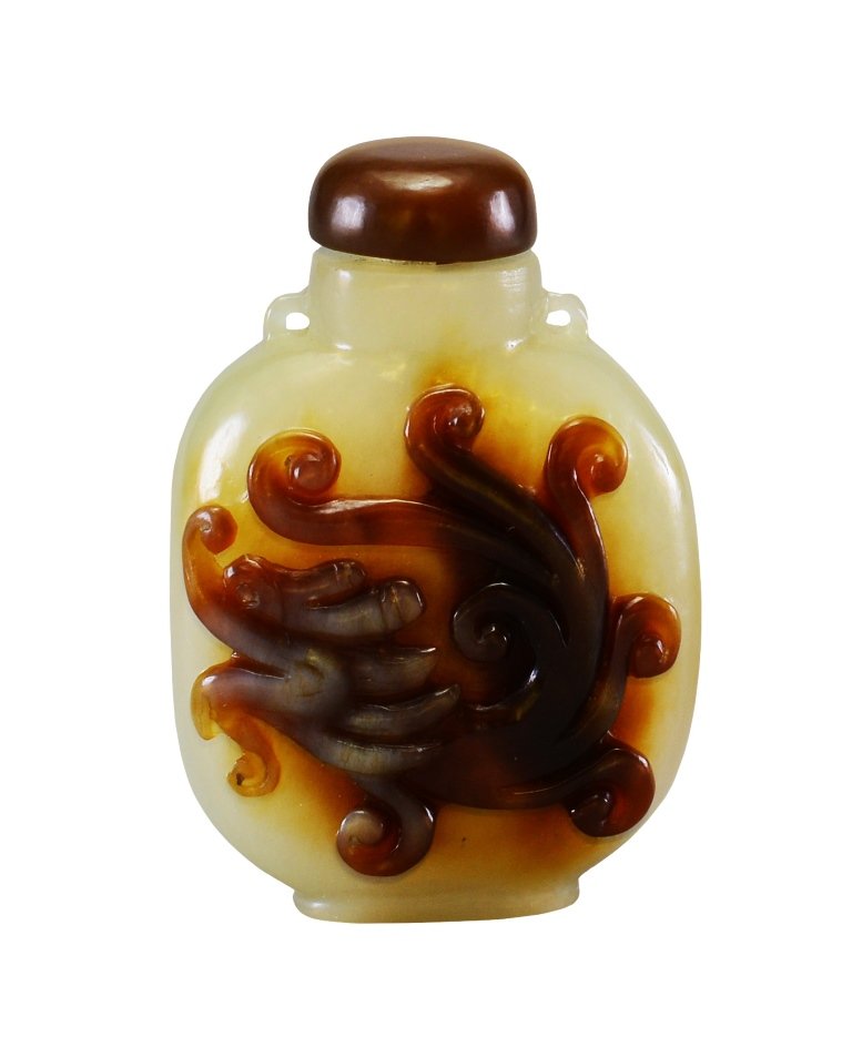 A CARVED AGATE SNUFF BOTTLE: The snuff bottle is pear-shaped. The exterior is decorated with imperial ruyi clouds in the middle and the top is decorated with a dark brown color. The snuff bottle is agate color. 2 1/16 in. (5.2 cm