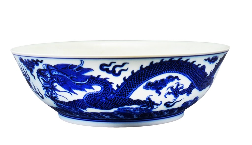 A BLUE AND WHITE DRAGON DISH: The bowls is concave-shaped. The exterior decorated with a dragon surrounded by ruyi clouds. The bottom with Chinese characters mark. 10 13/16 in. (27.5 cm) diameter, 3 1/2 in. (9 cm) tall. Qing Dynas