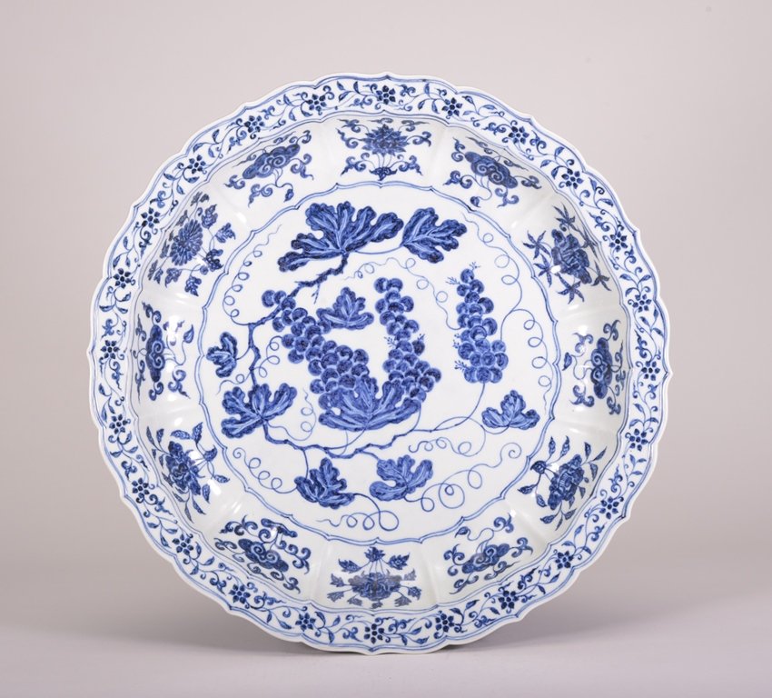 A LARGE BLUE AND WHITE DISH: The dish is concave-shaped and the exterior is decorated with numerous flower blossoms. Ming Dynasty 2 3/4 in. (7 cm) tall, 17 1/4 in. (43.8 cm) wide.