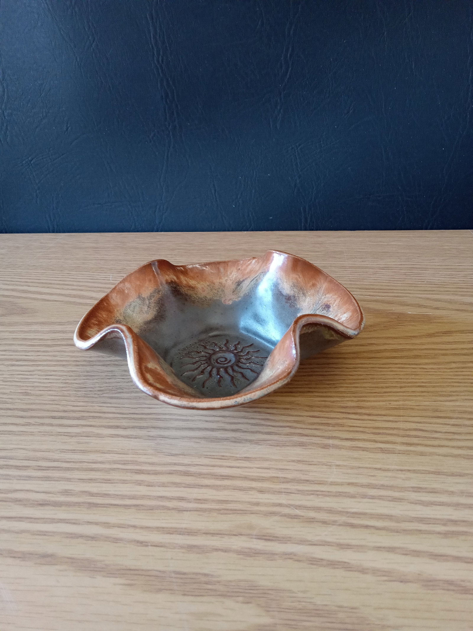 Ceramic Catchall Bowl: Ceramic Catchall Bowl-with a fluted, wavy rim and a raised sunburst medallion at the center. Roughly measures 6 inches. These items are part of an estate sale and we are a consignment based Auction