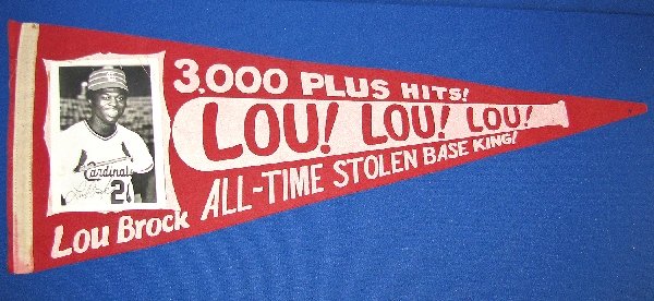 LOU BROCK 3,000 HITS FELT PENNANT: St. Louis Cardinals pennant features attached photo of Lou Brock. Commemorates 3000+ hits and all time stolen base king. Some creasing to photo. Pennant tip has a few small holes. Size: 29.5" long