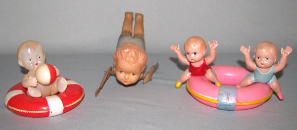 THREE JAPANESE CELLULOID BATH TUB TOYS: Two little boys on a life ring, a baby in a life ring, and a windup swimmer. There is some paint fading to back of boy's swimsuit, scratches to tin arms. Size: largest is 6 1/2" long, 2 3/4" tall