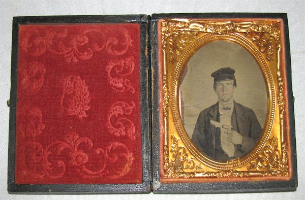 1/6 PLATE TINTYPE ARMED SAILOR OR SOLDIER IN LEATH: Most likely the image of a Union Sailor armed with a Model 1849 Colt pocket in embossed leather case. Minor damage to back of case and image shows some wear along left edge with some light spotting ab