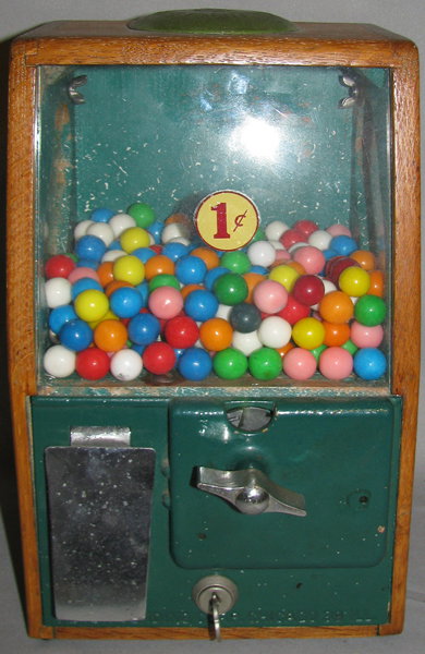 BABY GRAND GUM MACHINE BY VICTOR VENDING: Wood metal and glass gum machine from the 1950s is working and has original key. It has light age wear and a small chip of wood from the back panel. Size: 11 3/4" tall 7 1/8" wide