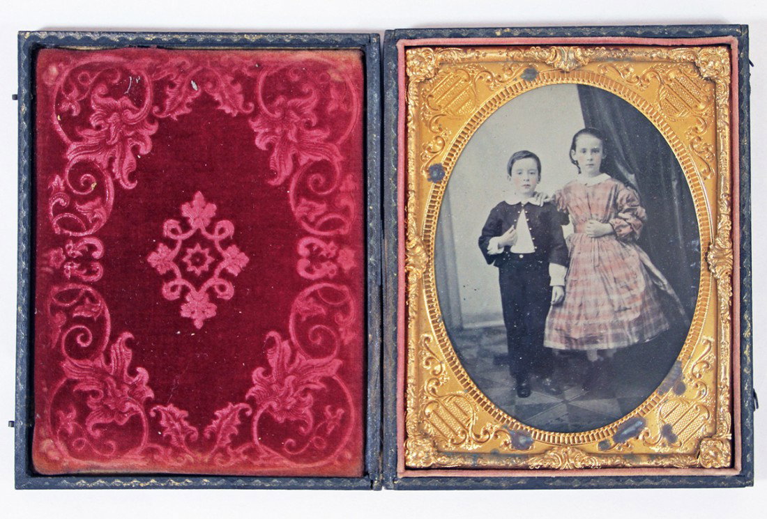 HALF PLATE AMBROTYPE OF BOY AND GIRL: Picture of a brother and sister in their Sunday best with hand tinted cheeks, lips and her pink dress, buttons on boy's jacket also hand tinted, housed in embossed leather case. Size: 6 inches by 4-3/