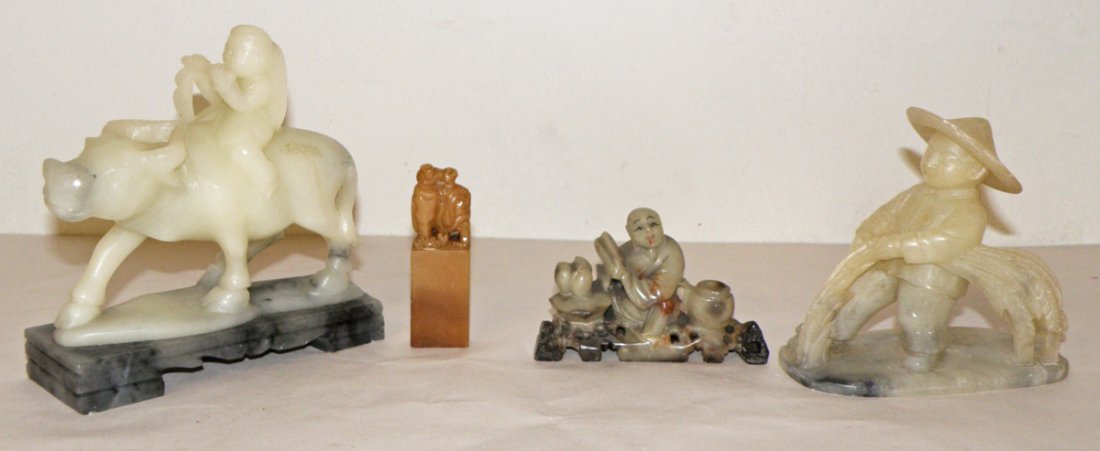 FOUR CARVED SOAPSTONE FIGURES WITH PEOPLE: Including man on elephant chop-mark, peasant riding water buffalo, peasant harvesting grain and figure with vase and table. Minor chipping to hat on peasant harvesting grain. Size: Largest: 4 3/4"