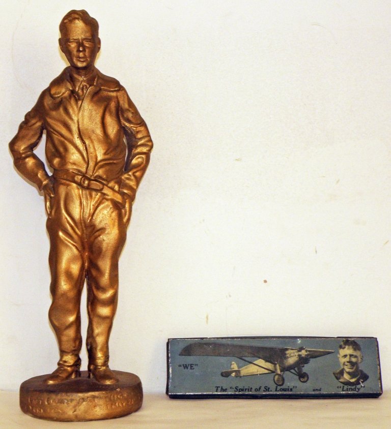 TWO CHARLES LINDBERGH ITEMS: Including a gold finished plaster statue and a tin litho pencil box. Some wear and scratching to pencil box. Pencil box: good. Size: 14" tall