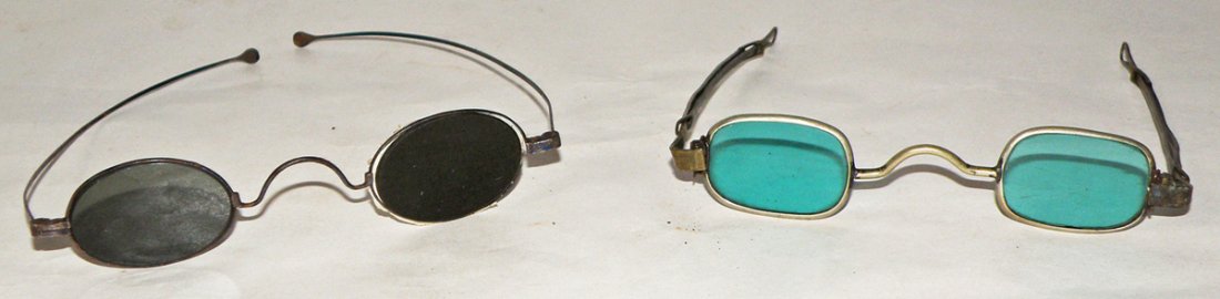TWO PAIRS OF CIVIL WAR ERA SUNGLASSES: One pair has adjustable length arms, the second pair has damage to one lense strap. Size: Largest: 4 1/2" wide