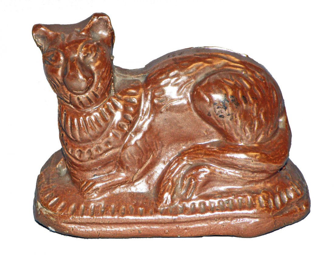 LYING DOWN CAT REDWARE STILL BANK: English brown glazed redware C-1910, has a factory defect to left side of cat's neck and a couple of small chips to coin slot. Ref. One Hundred Years of Ceramic Money Banks, by Beth Baddeley Huebner,