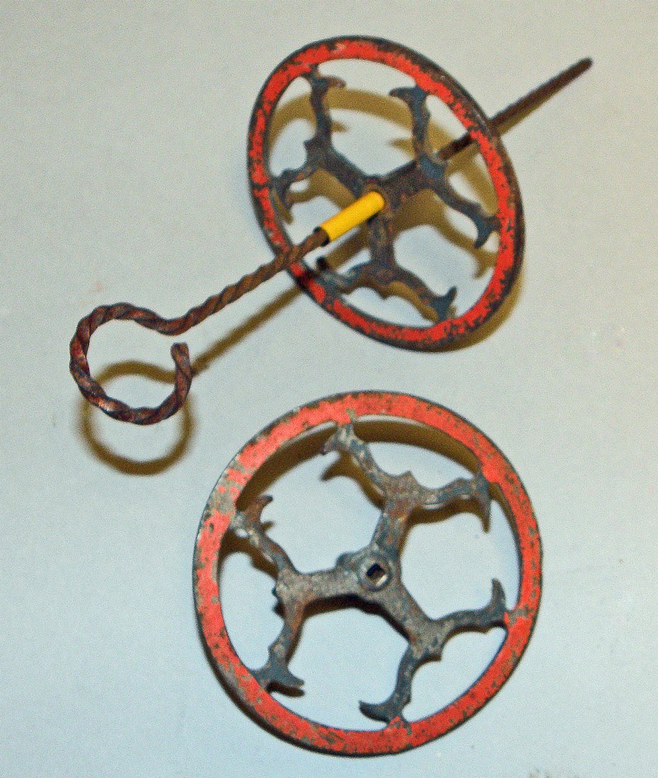 UNUSUAL AMERICAN CAST AND WROUGHT IRON SPINNING TOP: Twisted iron rod spins two cast iron painted tops. Late 19th early 20th century. Some paint chipping to both tops. Size: 9-1/4" long, 3-3/4" diam.