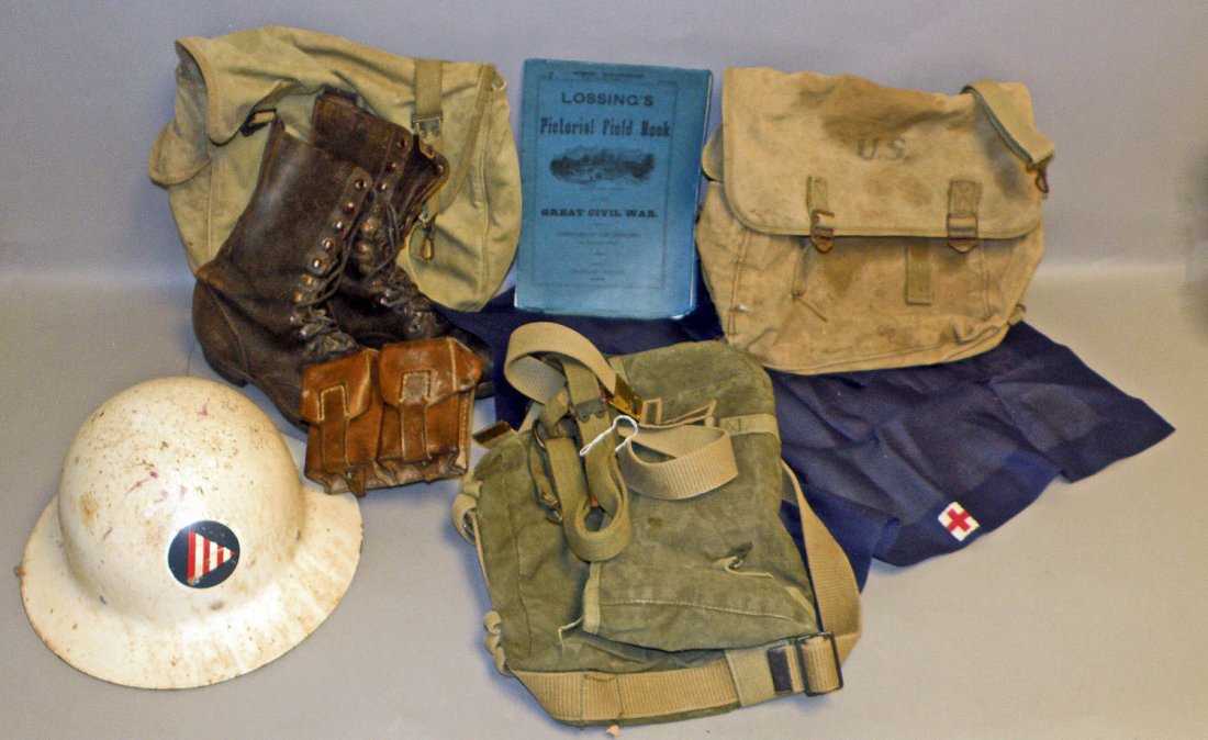 BOX LOT OF WWI AND WWII PERSONAL ITEMS: Includes boots, WWI cartridge box, three knapsacks, belts, Red Cross curtain, civil defense helmet, and a Civil War pictorial field book (1888). Size: Varies
