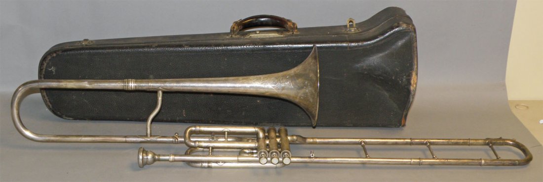 SLIDE VALVE TROMBONE IN ORIGINAL CASE: Made by G.G. Conn, Elkart, Indiana. Nickel plated brass. Has engraved horn. All valves intact and working. Some scattered dings. Original case has some wear and is Good. Size: 45" long