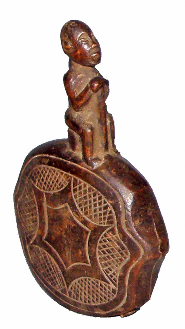 CARVED WOOD DIBU FROM THE CONGO: Made by the Kongo Peoples. Has original wood clackers and carved designs on sides. Wood has a couple old age splits. Provenance: Bernd Ratz, Maulbronn, West Germany, since the 1960s. Size: 7 3/4" tall