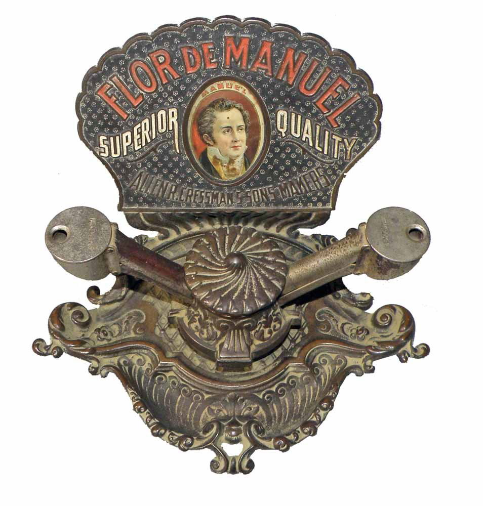 FLOR DE MANUEL DOUBLE CIGAR CUTTER: Scarce mechanical cast iron cigar cutter manufactured by Brunhoff, Cinncinatti, OH. Just the very slightest age and use wear. Some loss to nickel plated cutting arms. 6 1/2" tall, 10" long