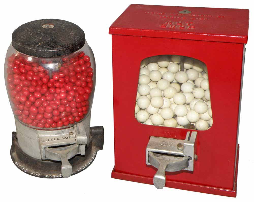 TWO LITTLE NUT VENDORS: One is a type A from 1934, glass and cast iron. Type A is book example, pg. 86. The other is a 1935 aluminum and iron box type vendor, also the book example, pg. 87. Largest 9 1/2" tall, 6 1/4" wide