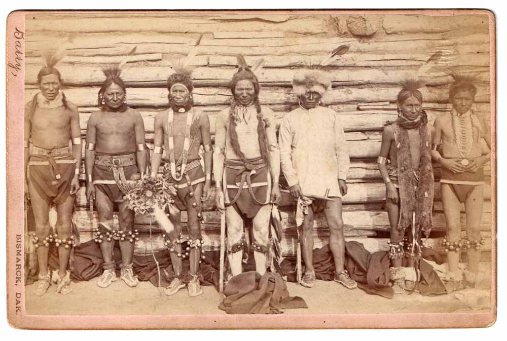 D.F. BARRY CABINET CARD PHOTO OF SIOUX DANCERS: Has original Bismarck, Dakota back stamp. Shows seven Sioux warriors dressed for ceremonial dance. Scarce image, only other example we can find is in the Denver Public Library Archives. Right side of 