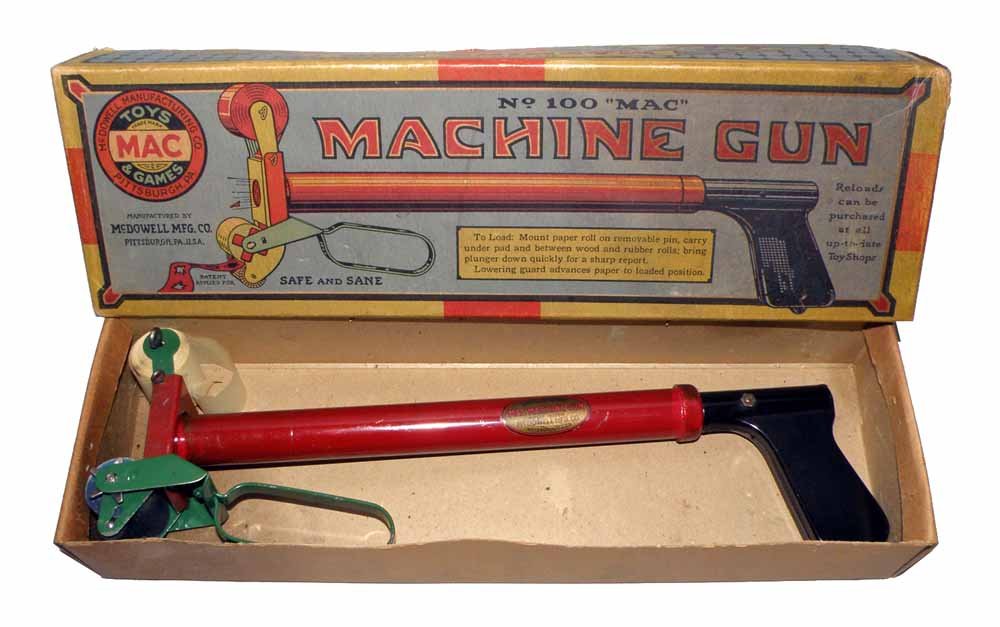 BOXED MAC NO. 100 MACHINE GUN: Complete toy shows just the slightest wear. Crisp original box has a couple small creases. The box grades excellent. 13 1/2" long, 4" wide