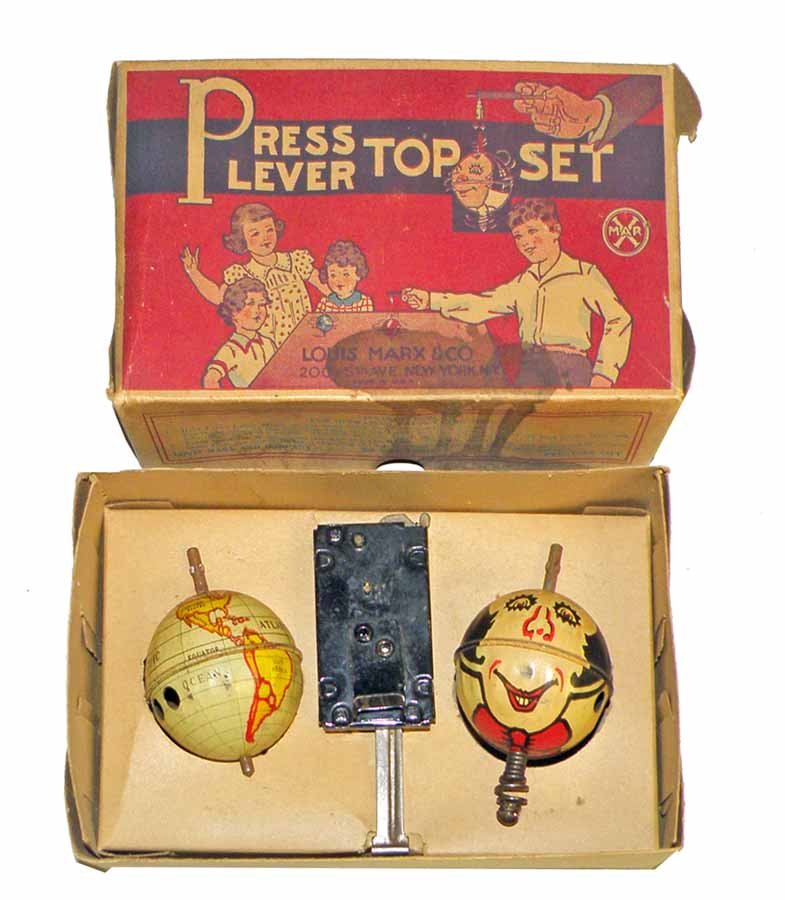 BOXED MARX PRESS LEVER TOP SET: Includes globe and two-face tops. Very minor wear. Box lid has some minor staining. Box grades very fine. 7-1/4" long