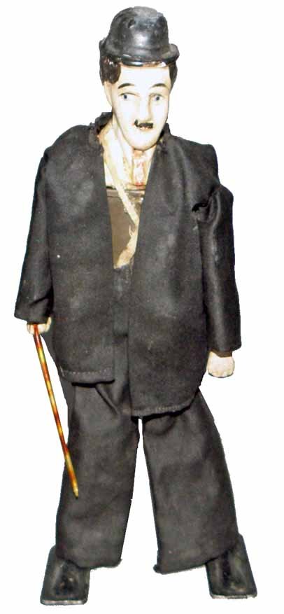 CLOCKWORK CHARLIE CHAPLIN: Composition head, original clothing over tin body. Wind-up walker works fine. Probably French. Circa 1925. Some minor splitting to seam in head.9 1/2" Tall