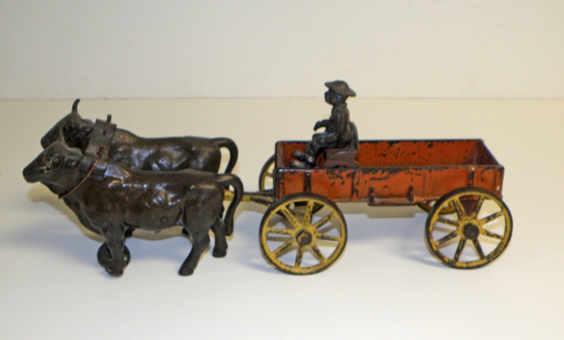 CAST IRON KENTON OX CART: Retains original yolk. Black driver possibly replaced. Scattered paint chipping. Also comes with a reproduction cast iron cart. 16" long