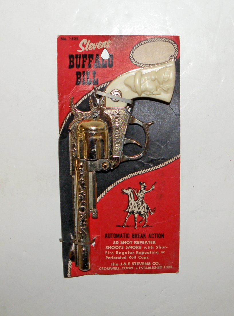 STEVENS BUFFALO BILL CAP GUN ON ORIGINAL CARD: Unplayed with die-cast cap gun has gold tone finish. Original card shows some wear and creasing with a VG rating 9" long